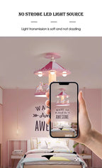 A hand photographing the pink carousel ceiling lamp with a phone in a bedroom