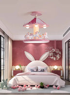 Carousel ceiling lamp above a pink bed with a wreath and ball garland decorations
