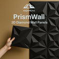 HighPeak PrismWall™ 3D Diamond Wall Panels in black with geometric texture held against a brown wall for modern decor.