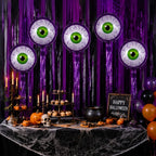 Purple Halloween Eyeball Balloons above a dessert table with cupcakes, pumpkins, and a Halloween sign.