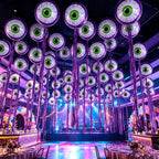 Purple Halloween Eyeball Balloons with long purple fringe decorating a colorful party hall ceiling.