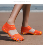 Quick-Dry Water Shoes orange pair worn at the beach, viewed diagonally from the side.