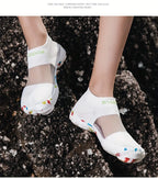 Quick-Dry Water Shoes white pair worn on dark shoreline rocks, viewed from above.