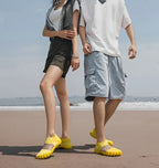 Quick-Dry Water Shoes yellow pairs worn by two adults on sand beside the water.