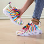 Rainbow Stripe Sneakers with one shoe held beside the matching shoe worn with jeans.