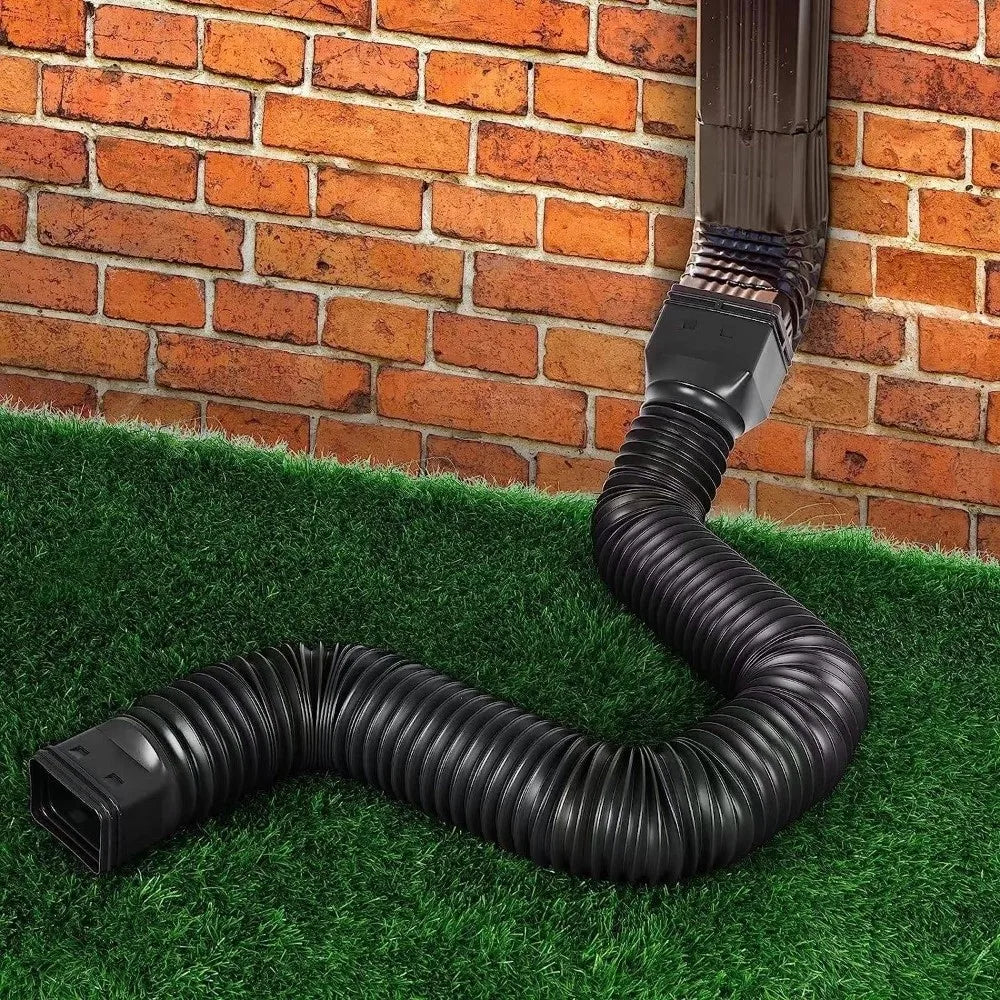 Retractable Downspout Extension in black curving across grass from a downspout beside a brick wall