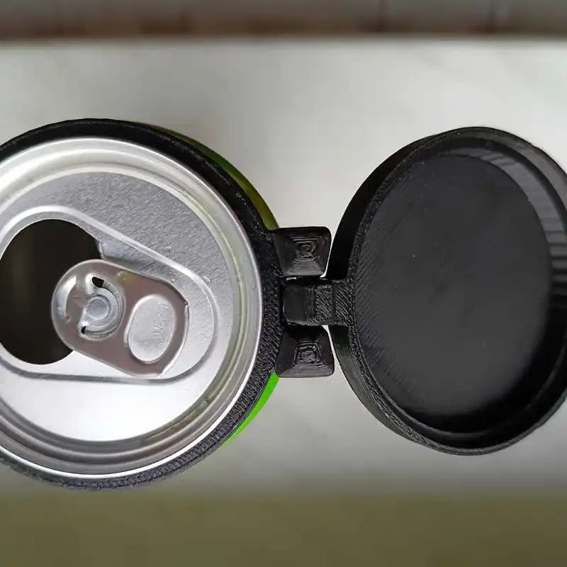 Reusable Soda Can Lid close-up showing its hinge, mounting ring and the open beverage can underneath.