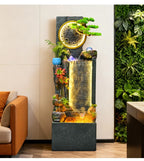 Rockery Water Fountain full-height view beside an indoor plant wall and orange seating.