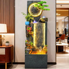 Rockery Water Fountain displayed against a showroom wall beside a wooden cabinet and lamp.