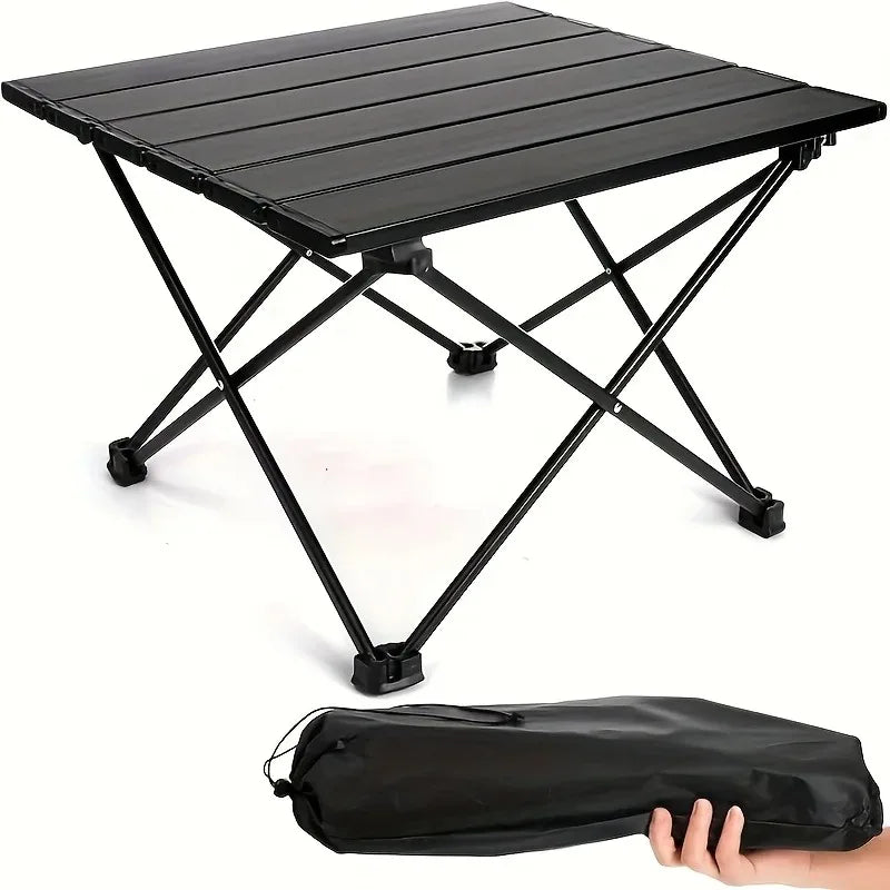 Roll-Up Camping Table black slatted tabletop and X-shaped legs, with a carry bag held below.