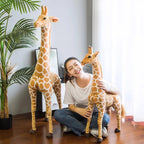 Safari Giraffe Stuffed Animal a seated woman holding the smaller of two giraffes.
