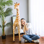 Safari Giraffe Stuffed Animal tall giraffe beside a cross-legged woman for scale.