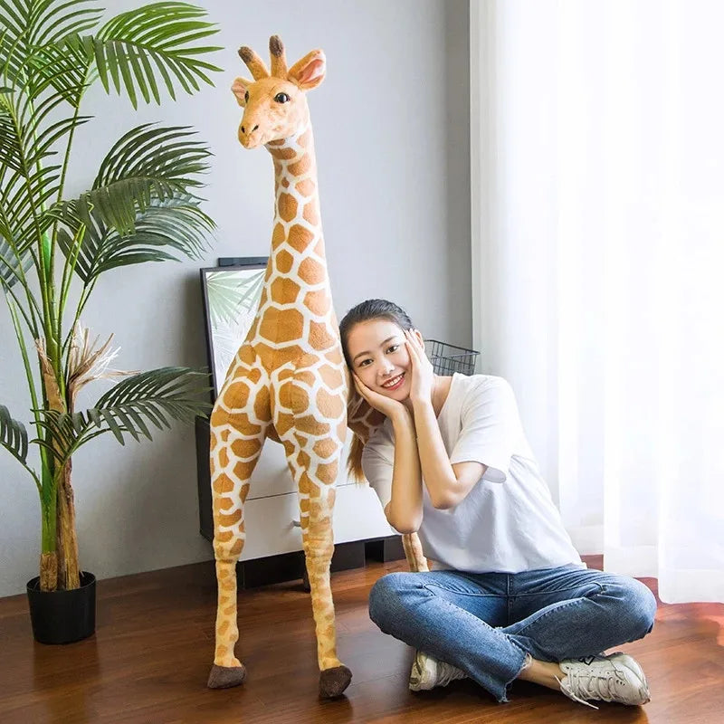 Safari Giraffe Stuffed Animal tall giraffe beside a cross-legged woman for scale.