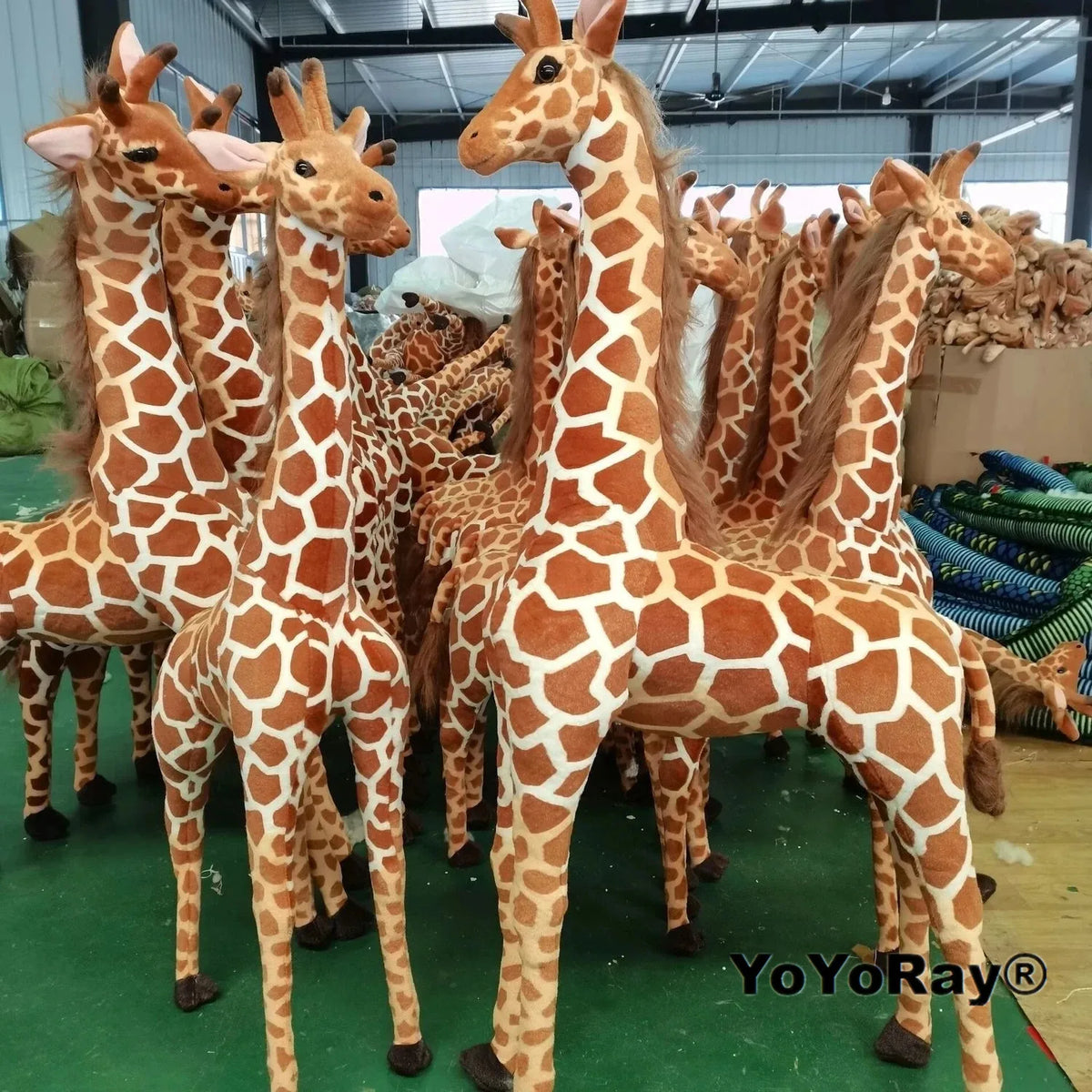 Safari Giraffe Stuffed Animal group of brown and cream giraffe plush toys in a supplier workshop.