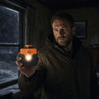 Saltwater Emergency Light held in one hand indoors, showing its orange cap and illuminated front LED