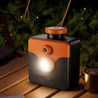 Saltwater Emergency Light illuminated on a wooden camping table beside a cup in an evening outdoor setting