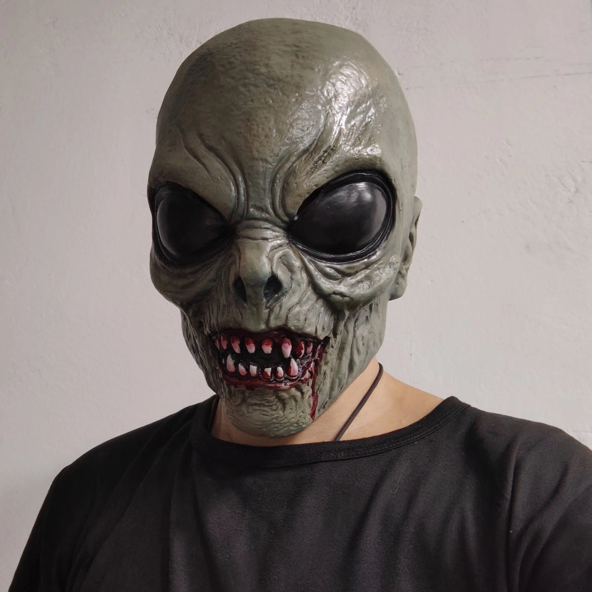Scary Alien Monster Mask worn with a black T-shirt, showing glossy black eyes and a toothy red-accented mouth.