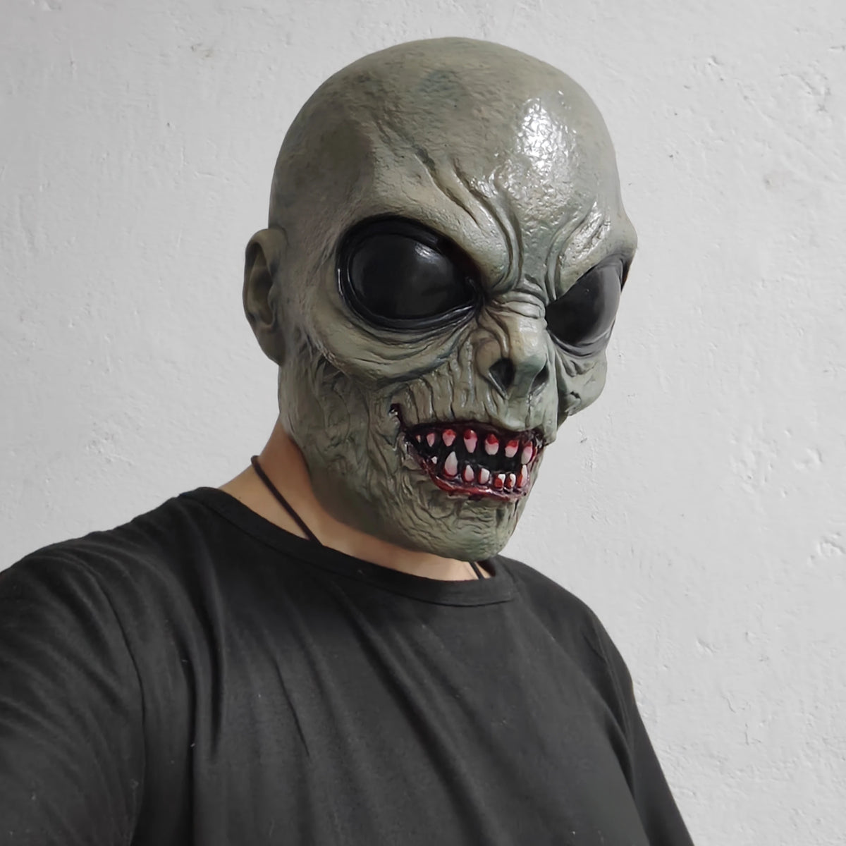 Scary Alien Monster Mask in a three-quarter view, showing its sculpted ear and wrinkled gray-green face.