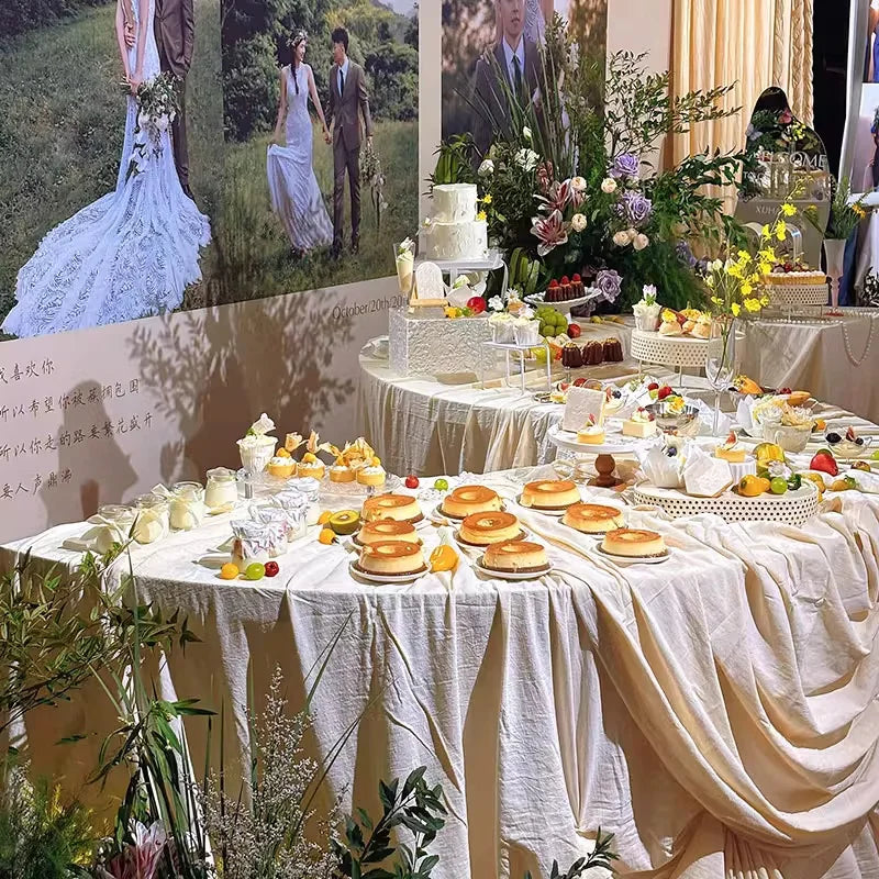 Serpentine Event Display Table styled with ivory linens, cakes, desserts and flowers at a wedding reception.