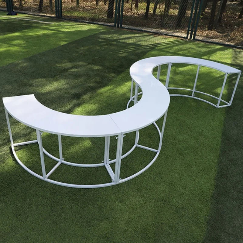 Serpentine Event Display Table white S-shaped arrangement on grass with the open support frame visible.