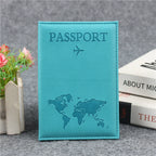 Signature Leather Passport Cover in Blue, a turquoise shade, standing beside books and flowers.
