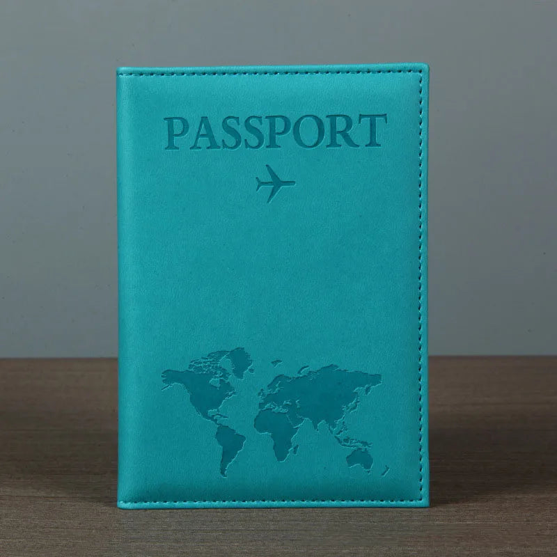 Signature Leather Passport Cover in turquoise Blue standing on a wooden tabletop with its map design visible.