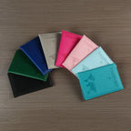 Signature Leather Passport Cover in all eight imported colors arranged in a fan on a wood surface.