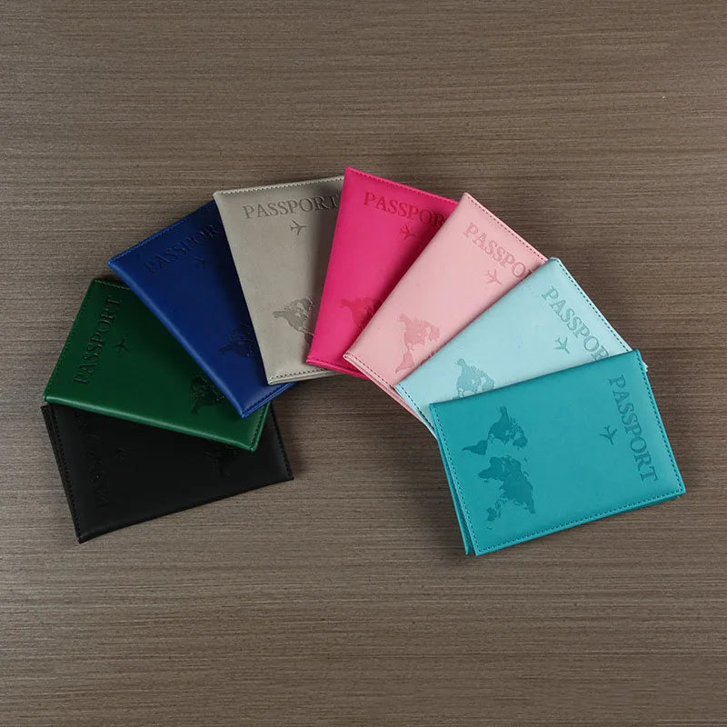 Signature Leather Passport Cover in all eight imported colors arranged in a fan on a wood surface.
