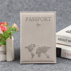Signature Leather Passport Cover in Gray, shown upright beside books and flowers with tonal passport lettering.