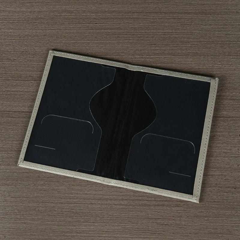 Signature Leather Passport Cover in Gray opened flat to show the dark interior document and card pockets.