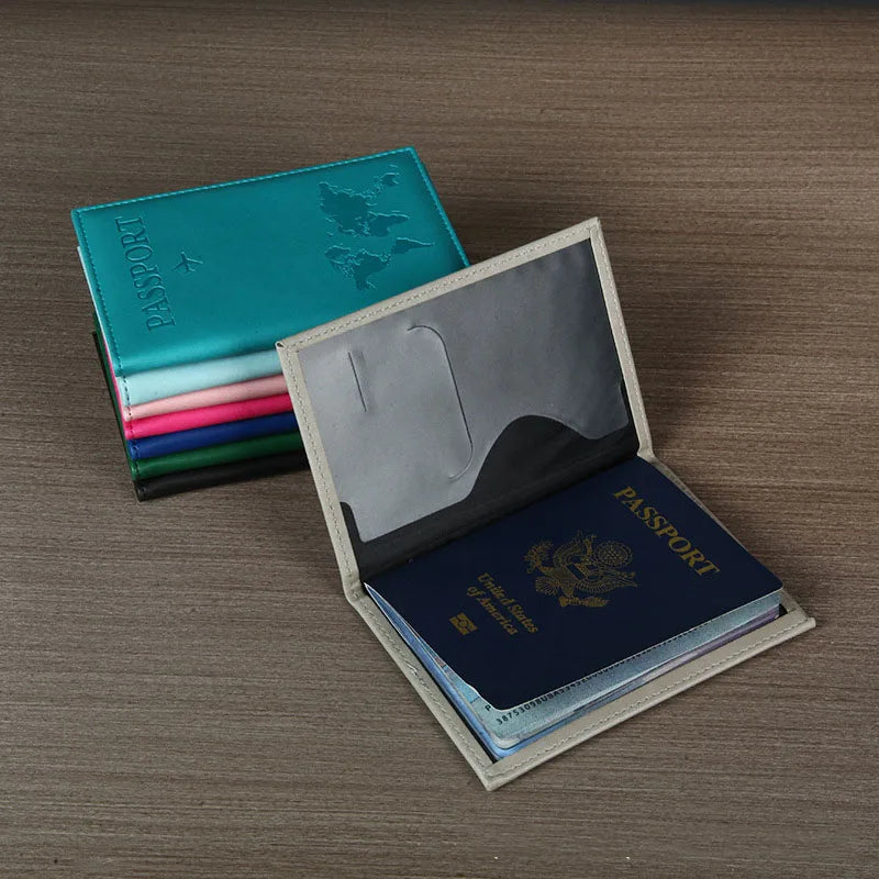 Signature Leather Passport Cover in Gray opened with a passport inside, beside a stack of colored covers.