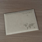 Signature Leather Passport Cover in Gray unfolded on a wood surface to show its front and plain back.