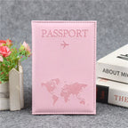 Signature Leather Passport Cover in Light Pink, standing beside books and flowers with its world-map front visible.