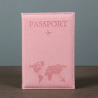 Signature Leather Passport Cover in Light Pink standing on a wooden tabletop against a plain gray background.