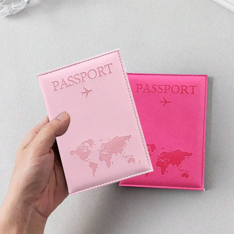 Signature Leather Passport Cover in Light Pink held in one hand, with a Rose Red cover resting behind it.