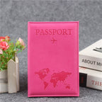 Signature Leather Passport Cover in Rose Red, a hot pink shade, shown upright beside books and flowers.