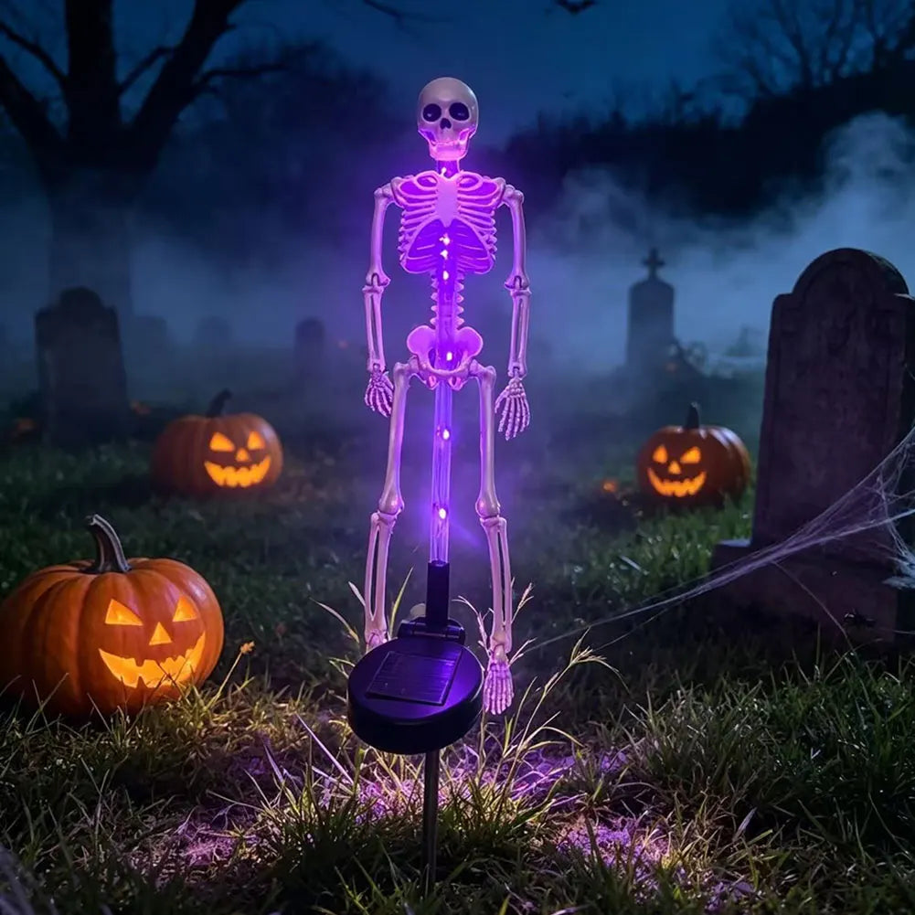 Purple skeleton solar garden light with visible solar panel among Halloween pumpkins