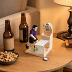 Soccer Goal Bottle Opener on a table with bottles, snacks, and a loose bottle cap