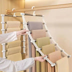 Space Saving Pants Hanger holding folded trousers while a person tilts the front rack outward in a wooden closet.