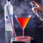 Spiral Straw Cocktail Glass filled with an orange drink while a fine mist is sprayed above it