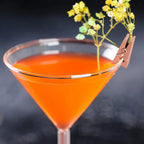 Spiral Straw Cocktail Glass bowl close-up with an orange drink and clipped yellow floral garnish