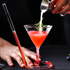 Spiral Straw Cocktail Glass on a bar mat as a drink ingredient is poured from a metal jigger