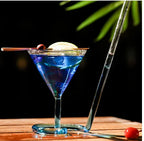 Spiral Straw Cocktail Glass holding a blue drink with lemon and cherry across the rim