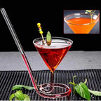 Spiral Straw Cocktail Glass holding a red drink on a black bar mat beside fresh mint