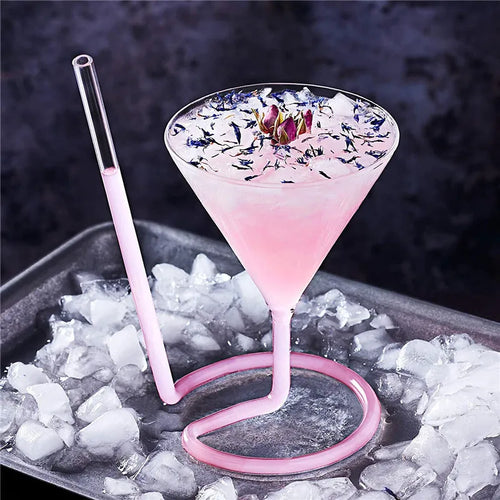 Spiral Straw Cocktail Glass filled with a pink drink and floral garnish on an ice-covered tray