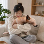 Squatting Dog Plush Toy woman in a cream sweater holding the plush dog while seated cross-legged.