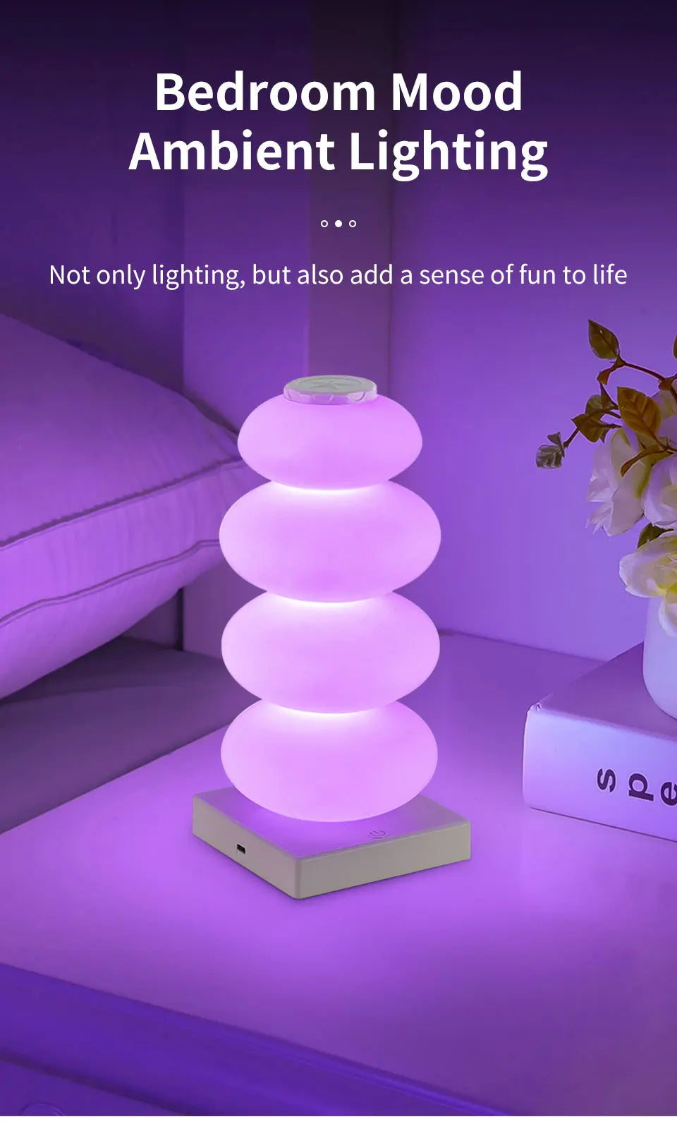 Stacked Pebble RGB Lamp glowing purple on a bedside table beside flowers.