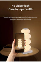 Stacked Pebble RGB Lamp glowing warm white behind a phone showing the same lamp.
