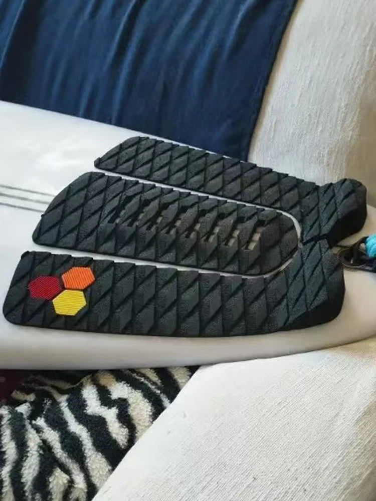 Angled close-up of the black diamond-textured surfboard traction pad and raised tail edge