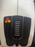 Close-up of black diamond grip, center slots and red, orange and yellow accents on the surfboard pad